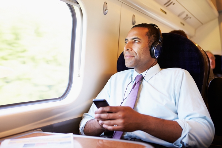 Man on train wearing headphones while looking out the window